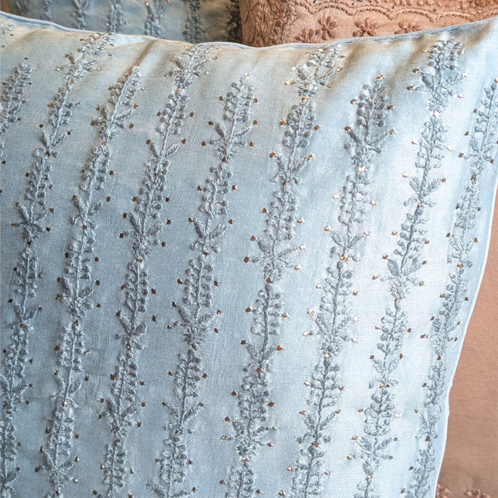 Close-up of a light blue chikankari cushion cover intricate pattern.