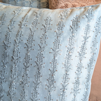 Close-up of a light blue chikankari cushion cover intricate pattern.