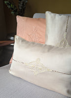 Decorative chikankari pillows with lace details on a couch