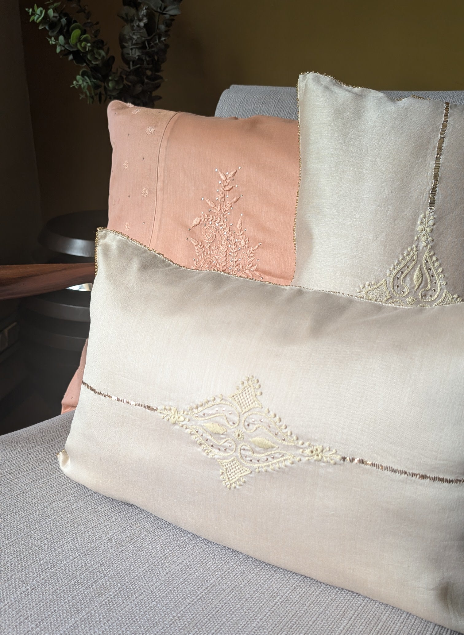 Decorative chikankari pillows with lace details on a couch