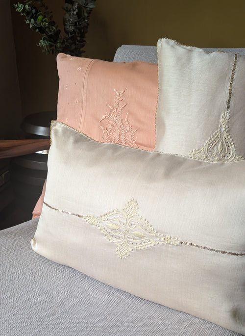 Decorative chikankari pillows with lace details on a couch