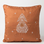 Chikankari orange throw pillow featuring a white embroidered paisley motif in the center and small white embroidered flowers scattered around it, set against a plain light gray background.