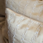 Close-up of beige fabric with intricate white embroidery